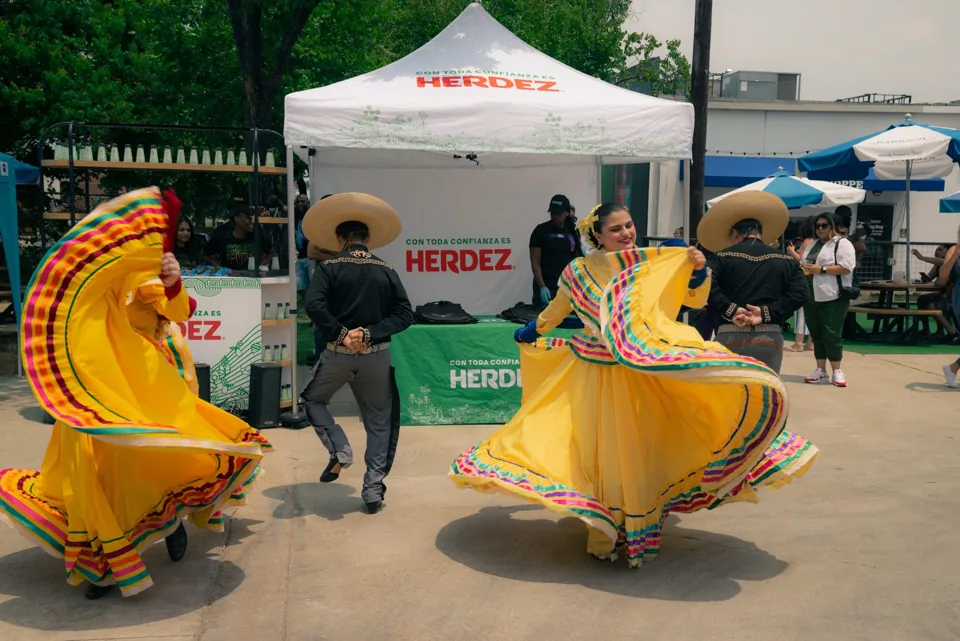 Folklórico dancers performing in vibrant yellow skirts at Sazón