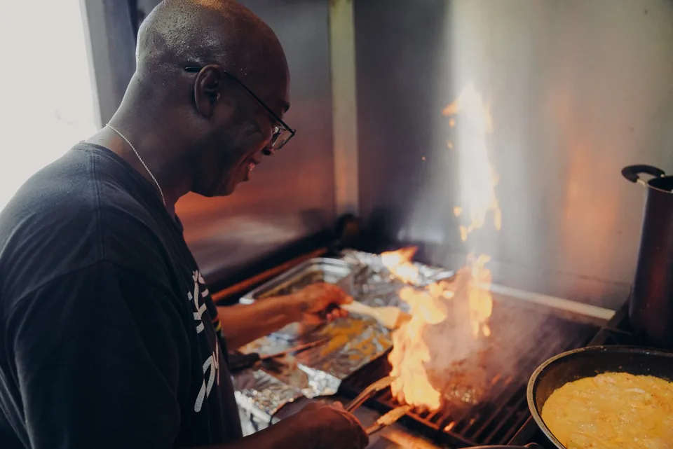 A festival vendor grilling food over open flames
