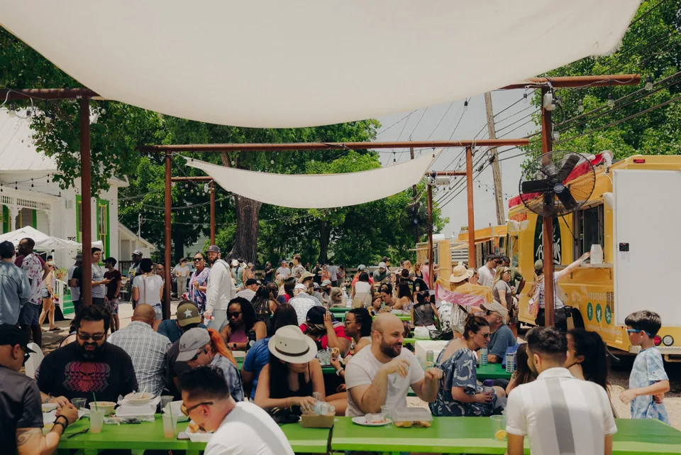 Families enjoying Sazón Latin Food Festival beneath white shade sails