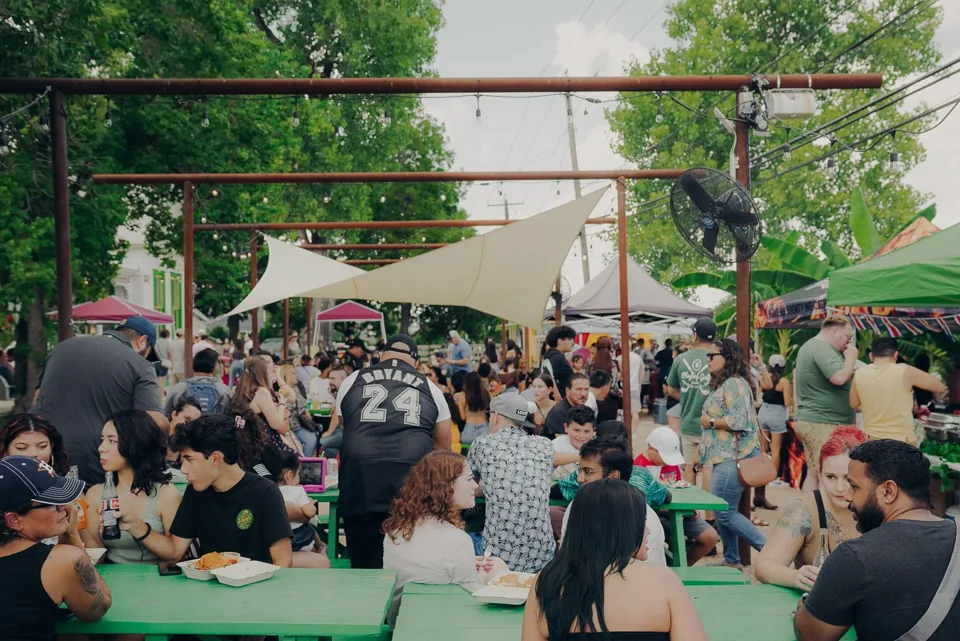 Festival guests gathering in a tree-lined courtyard at Sazón Latin Food Festival