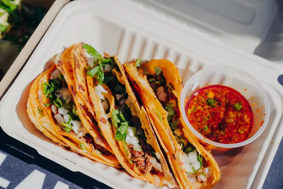Birria tacos topped with cilantro and served with dipping broth