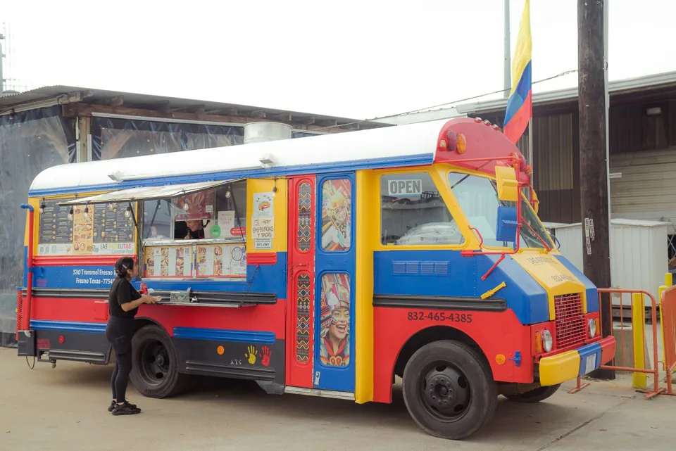 A colorful Latin American food truck bus parked at the festival