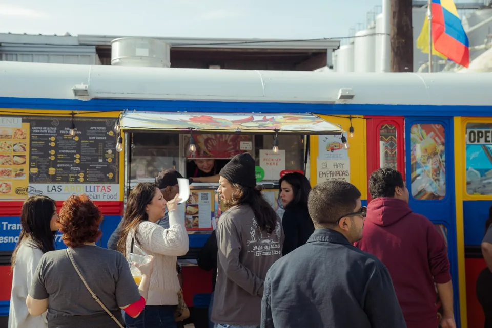 Customers lining up to order from a colorful Latin American food truck
